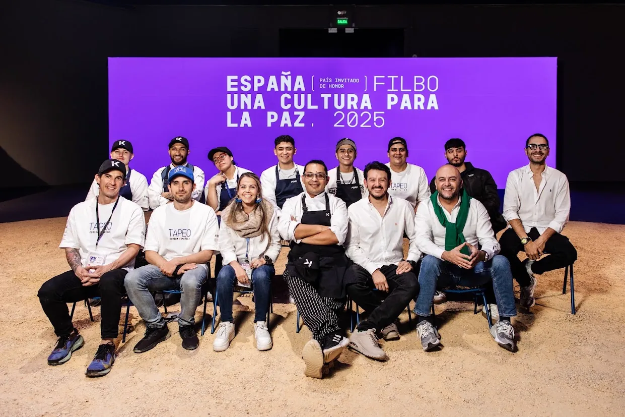 El equipo de Fork, trece personas en uniforme, sentadas frente al telón de la Feria del Libro de Bogotá
