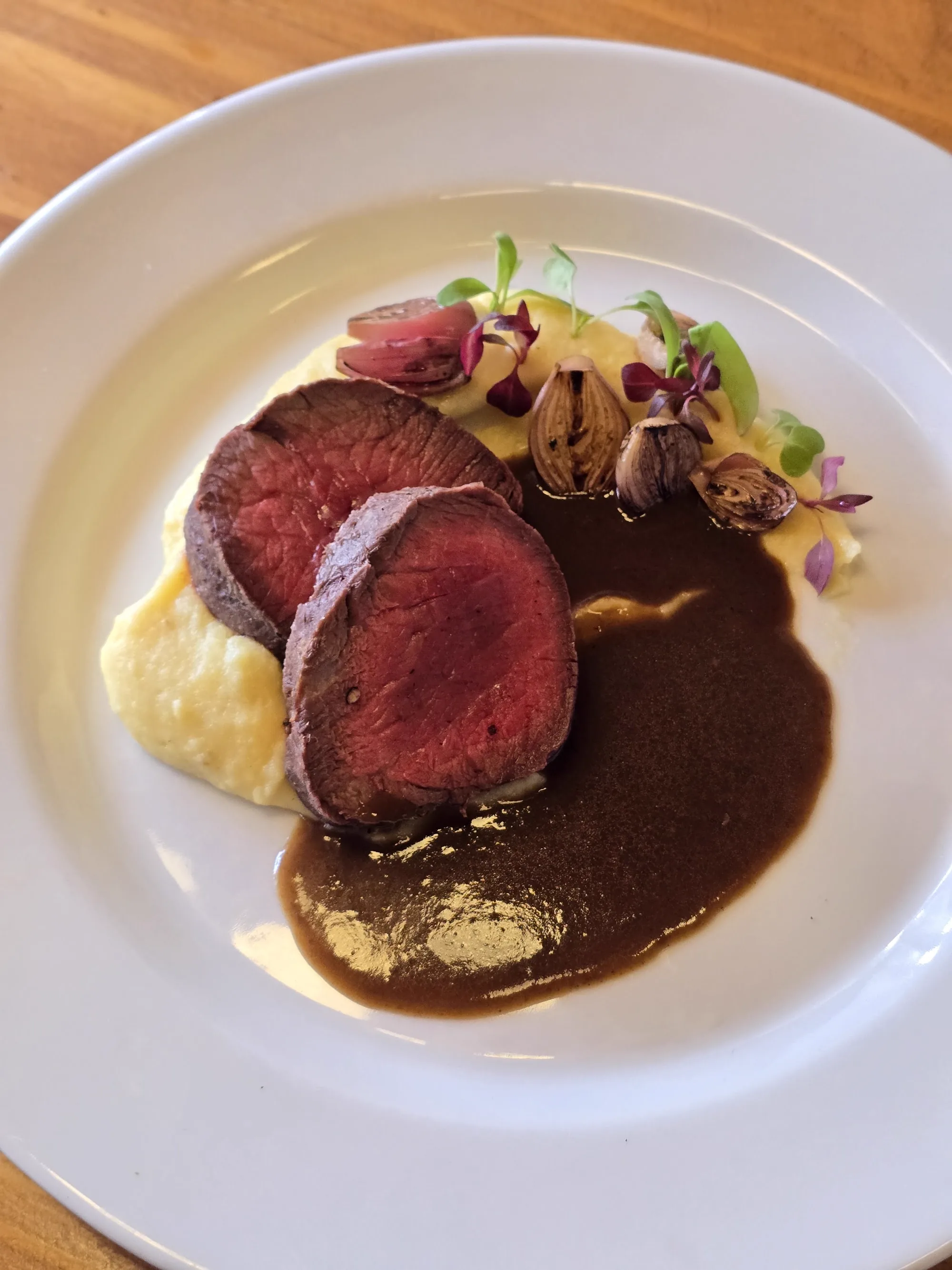 Res en su punto sobre puré, con echalote asado y jugo oscuro